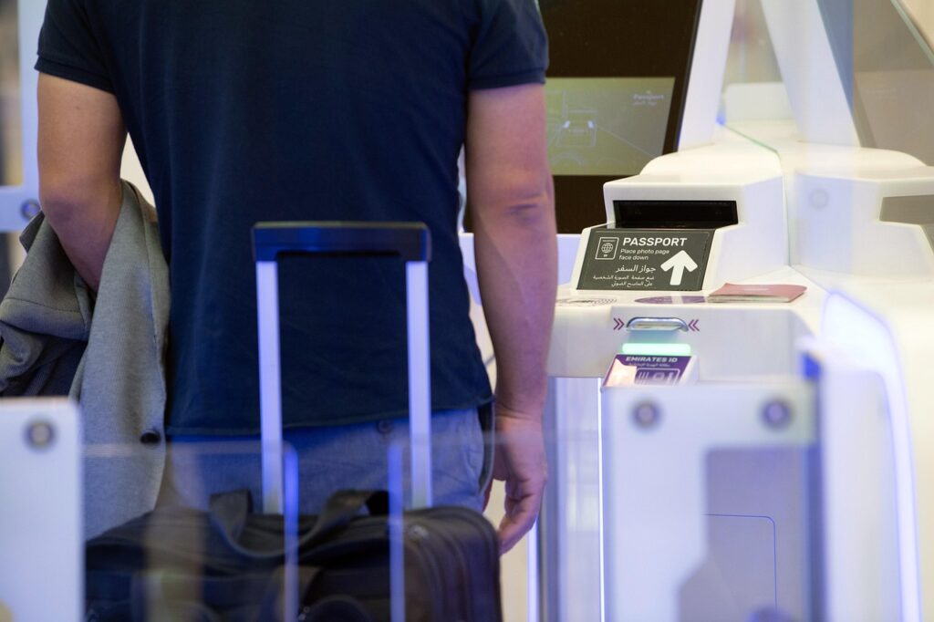 Passenger placing a carry‑on into an overhead bin with a compare-fare display showing “No carry‑on fees” across EU flights.