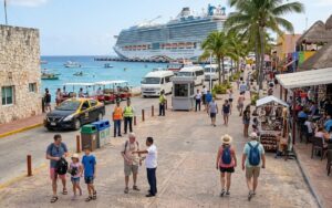 Tourists walk along a Mexican cruise port waterfront with a large cruise ship docked, as Mexico reports record international visitor numbers through July 2026.